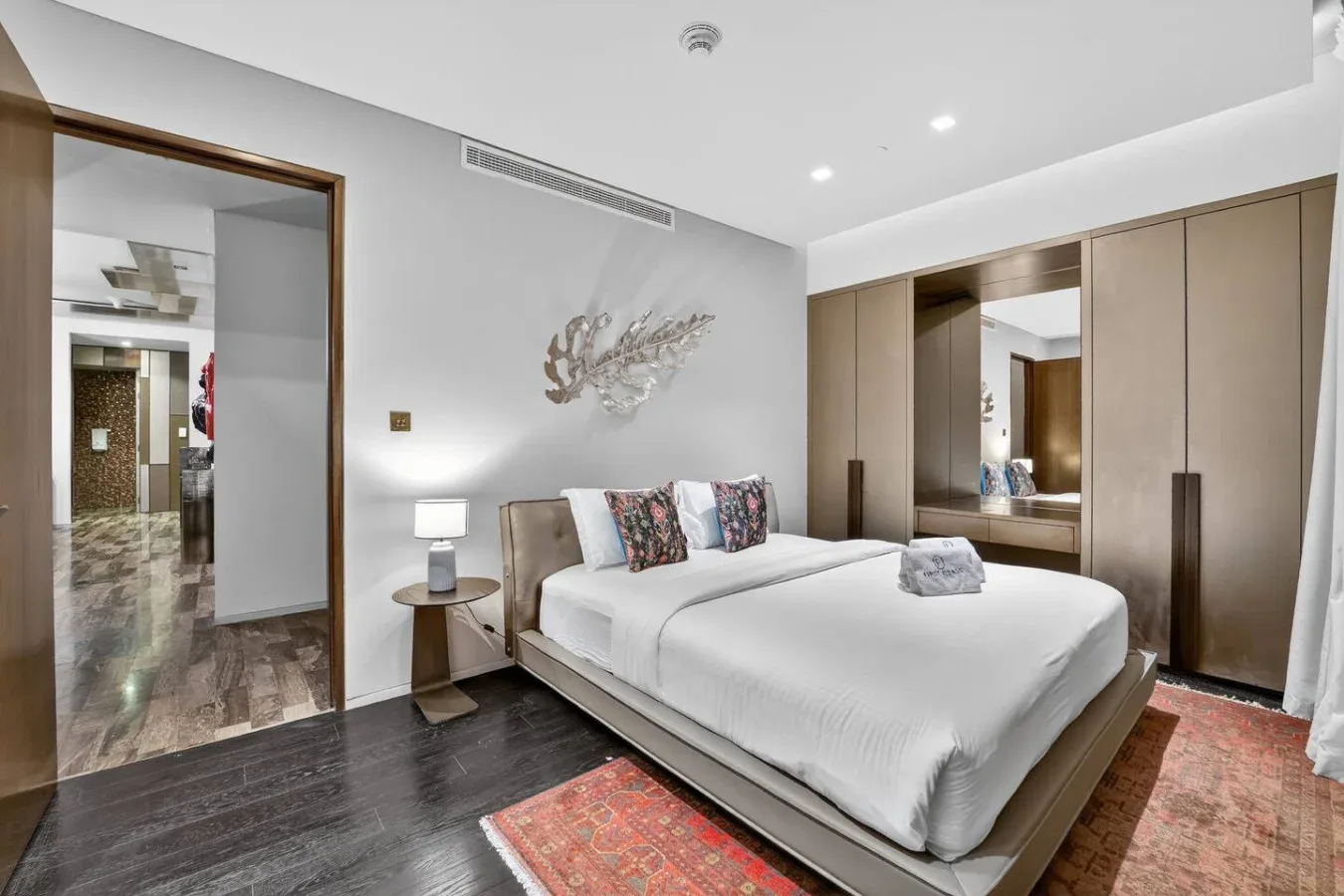 A bedroom with a neatly made bed, bedside tables, and built-in wardrobes.