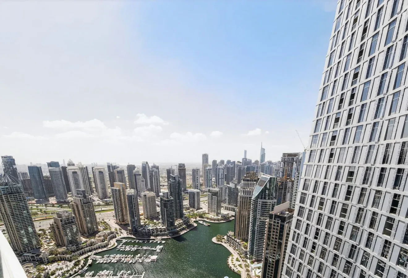 A city skyline overlooks a curving waterway and marina.