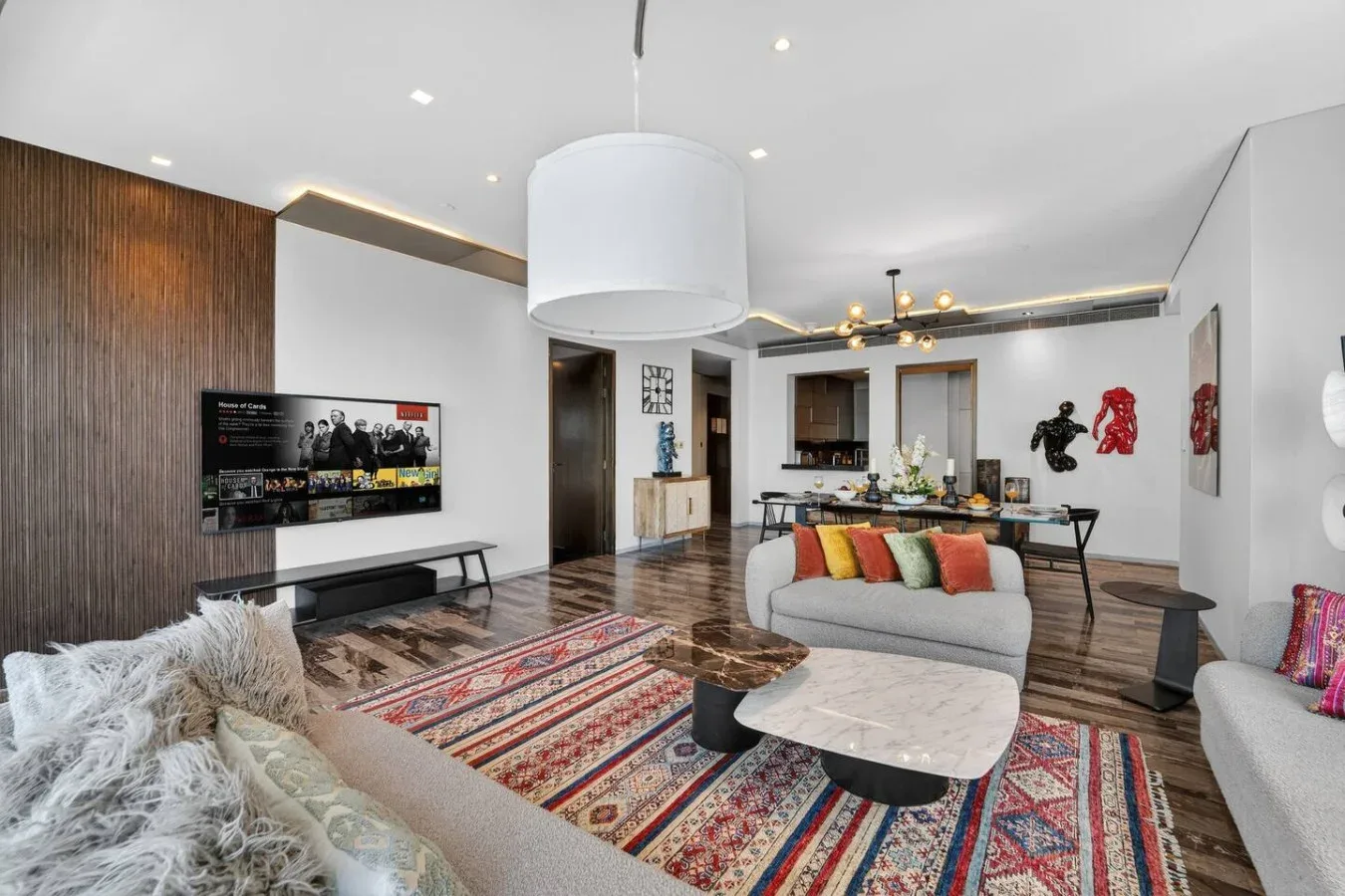 A bright living room with a television, colorful rug, and seating around a coffee table.