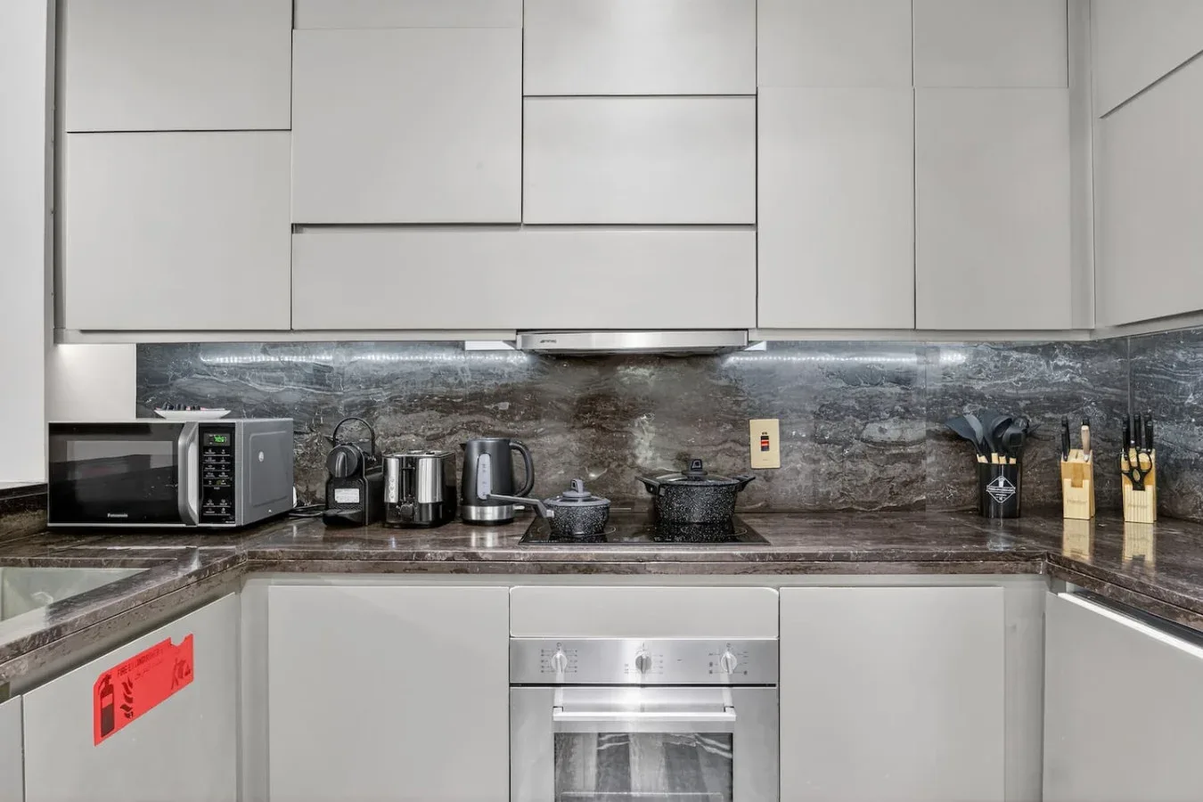 A modern kitchen with white cabinets, a dark countertop, and built-in appliances.