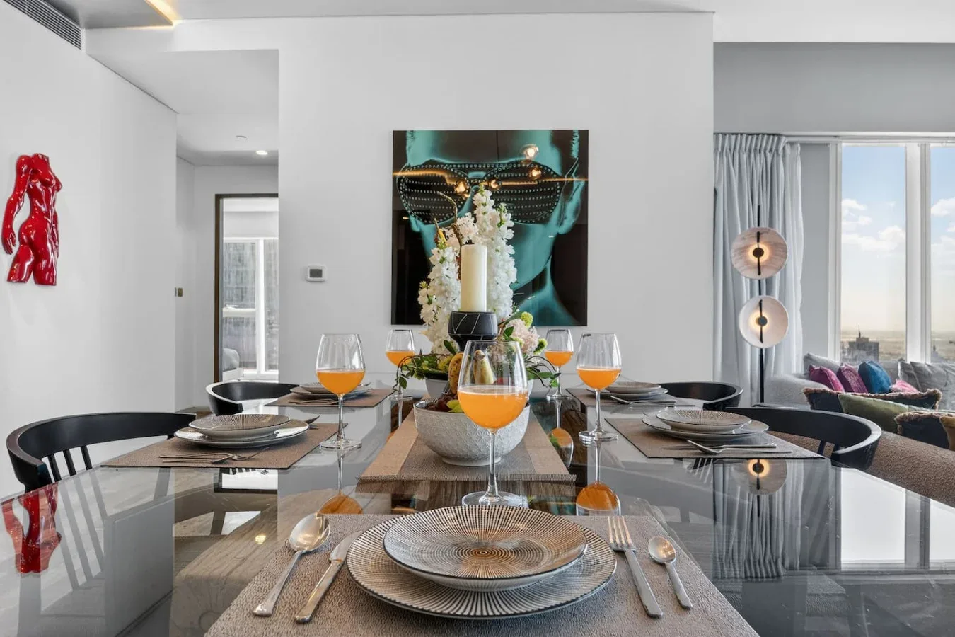 A modern dining area with a set table and large artwork on the wall.