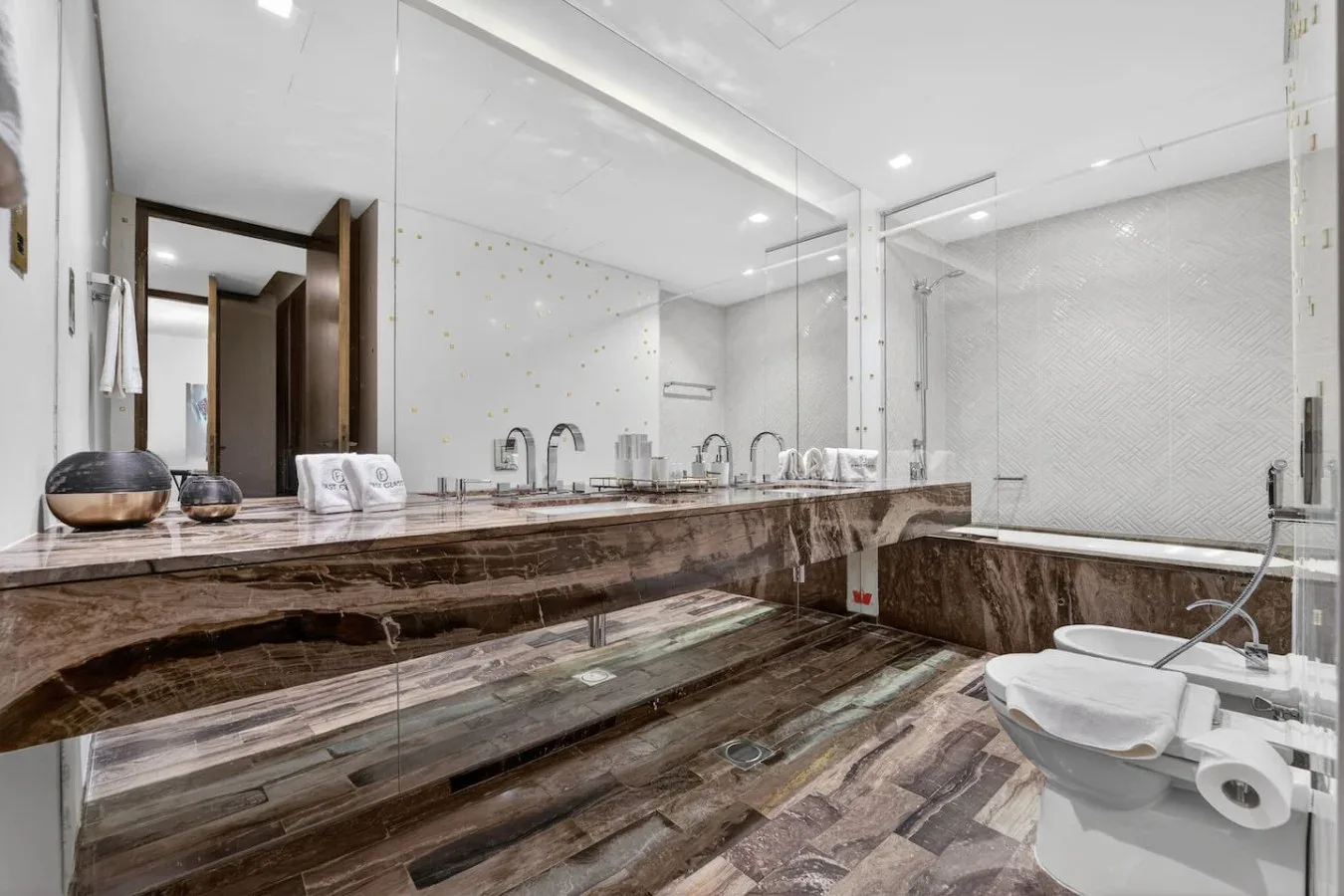 A bright bathroom with a long vanity and a glass-enclosed shower.