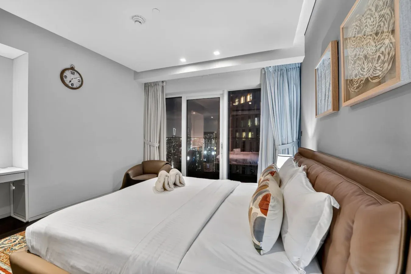 A bedroom with a large bed, bedside seating, and curtains by the window.