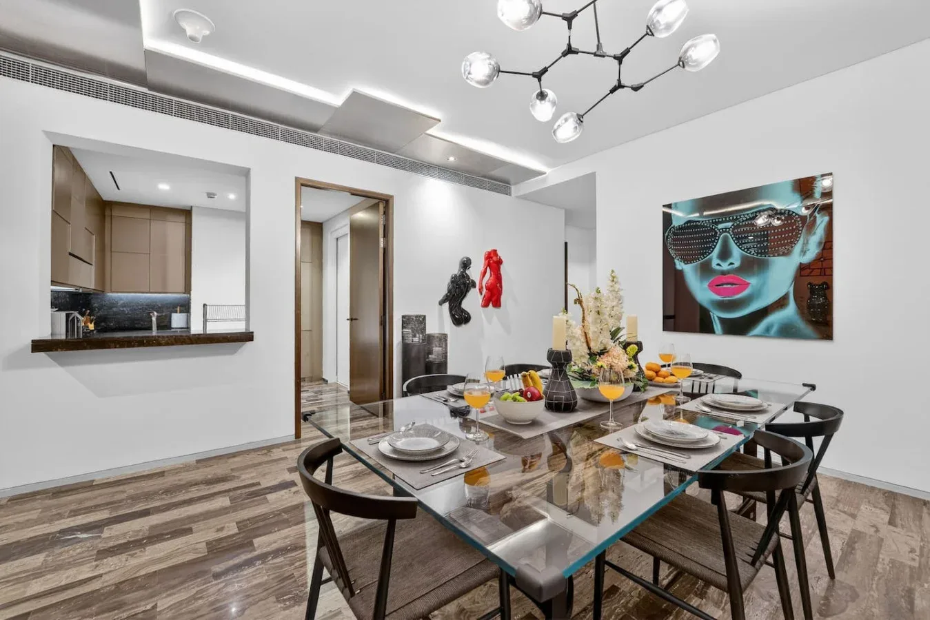 A dining area with a glass table set with dishes and fruit.