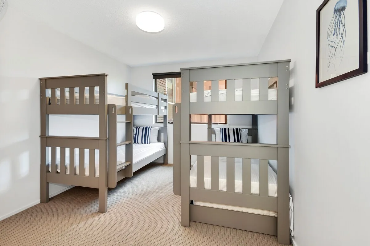 Un dormitorio con literas, ropa de cama a rayas y un cuadro enmarcado.