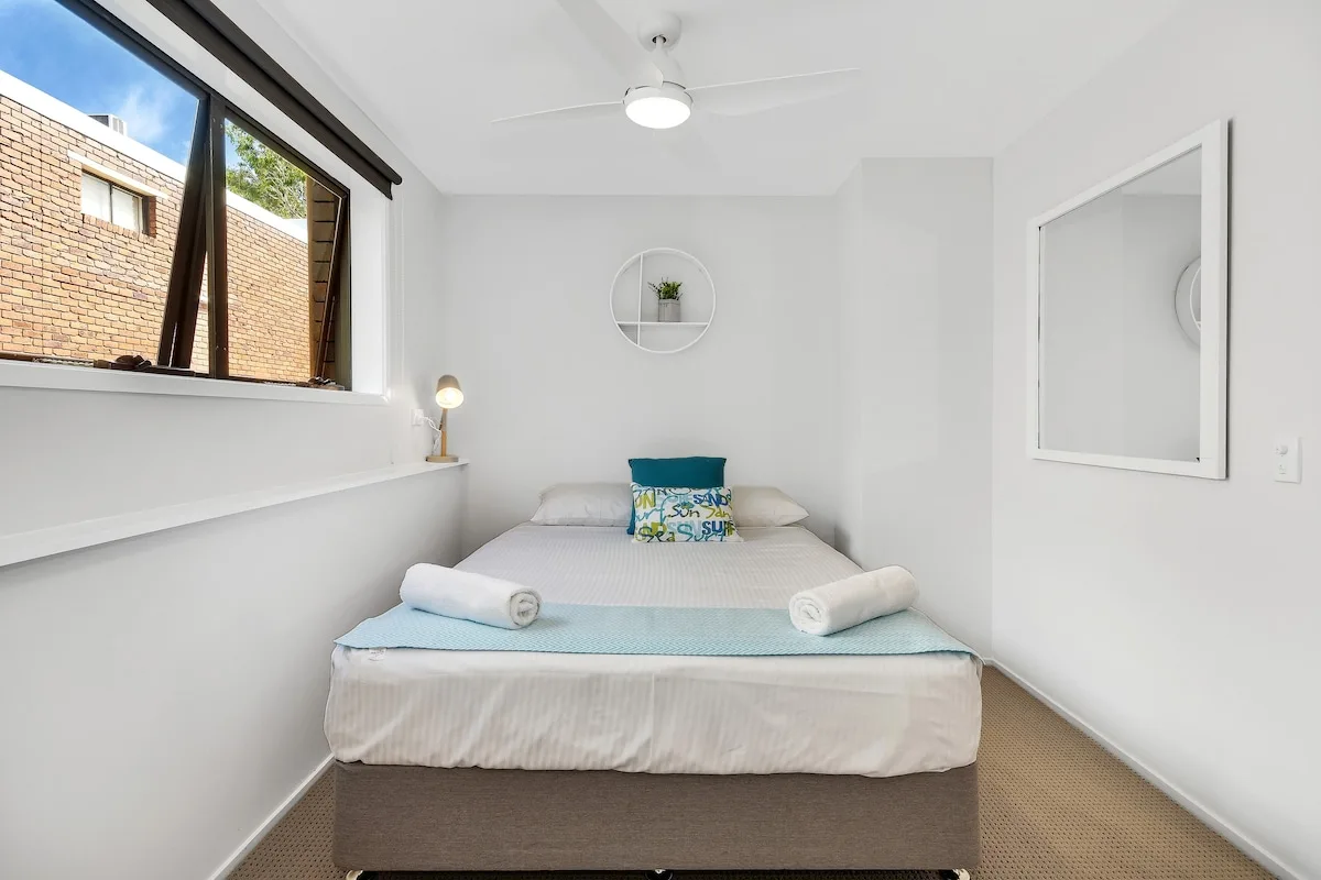 Un dormitorio con una cama bien tendida y una ventana grande.