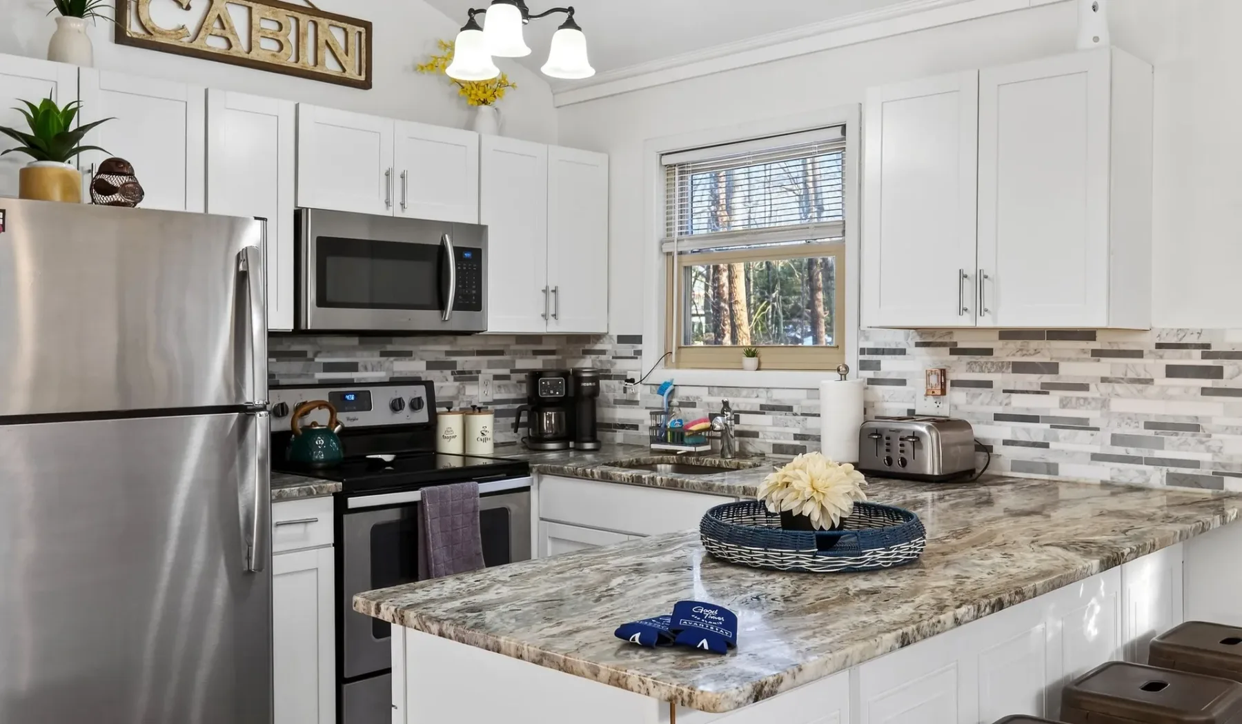 A bright kitchen with white cabinets, stainless steel appliances, and a central island.