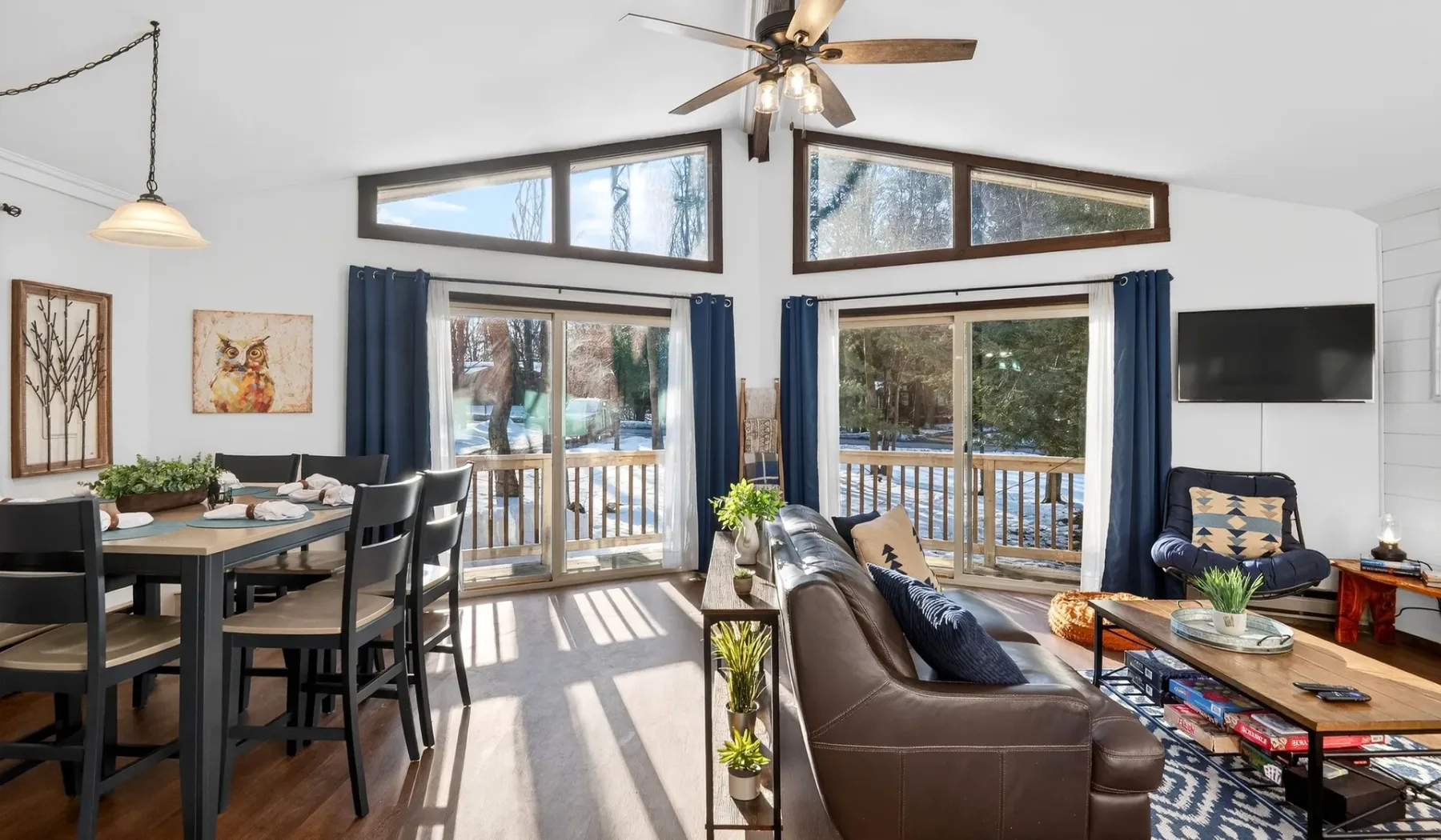 An open living and dining area with seating, a dining table, and large windows.