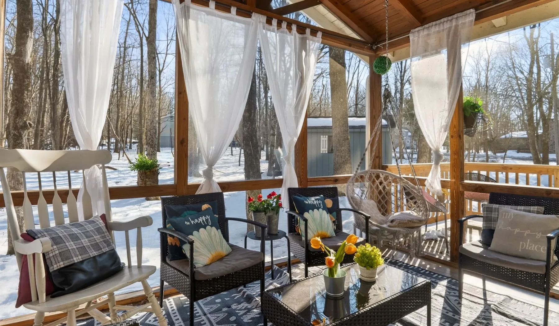 A covered outdoor seating area with sheer curtains and a glass-topped table.