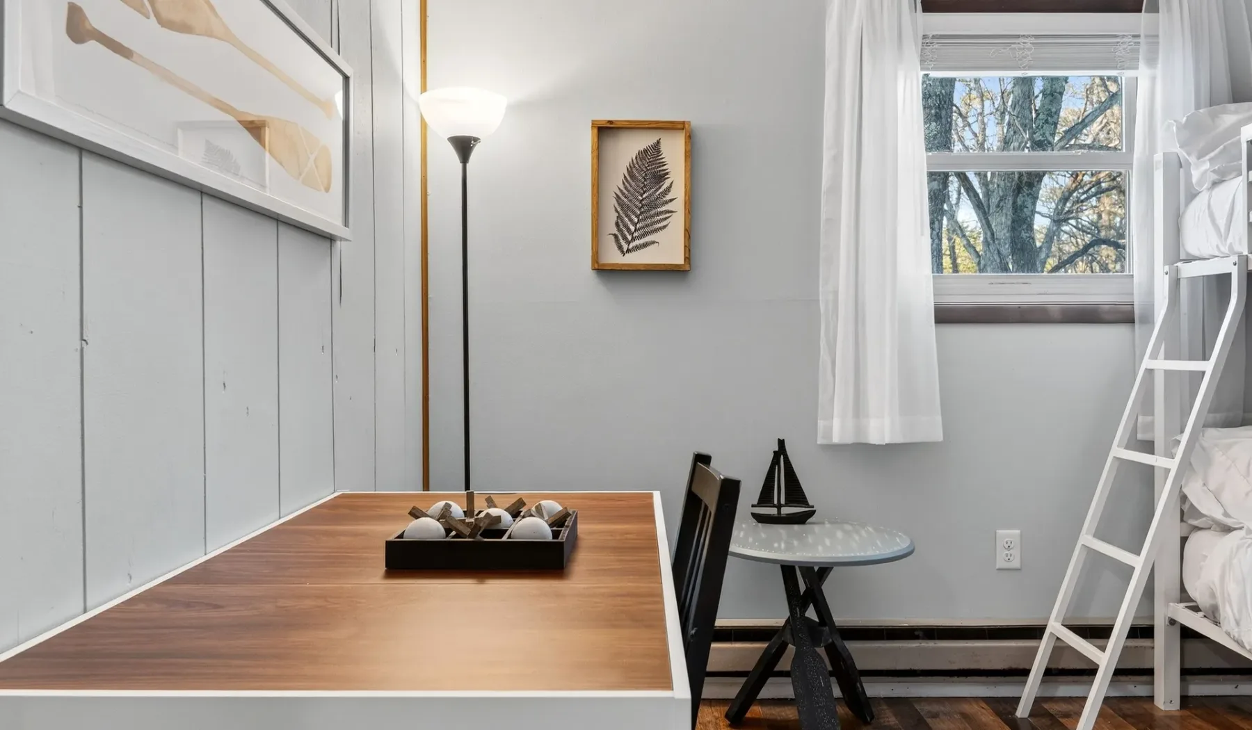 A compact bedroom with a wooden table, window, and bunk bed.