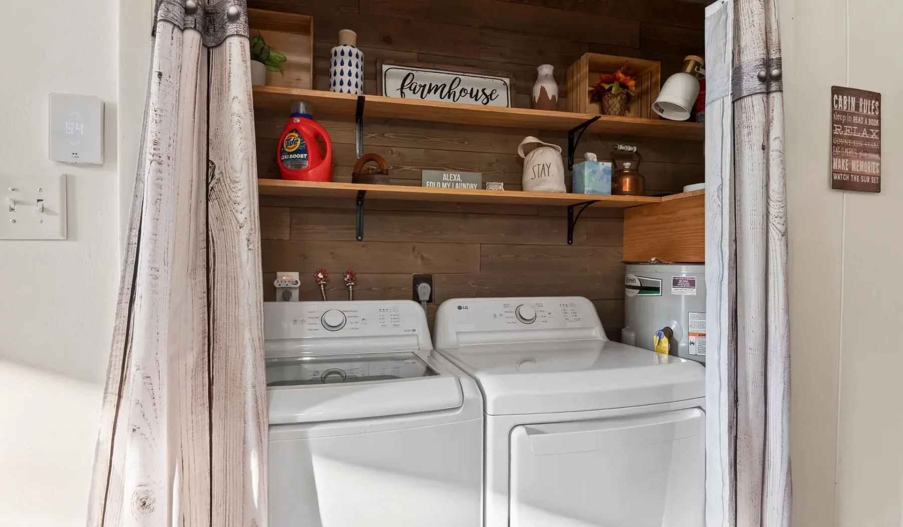 A laundry area with two washing machines beneath wooden shelves.