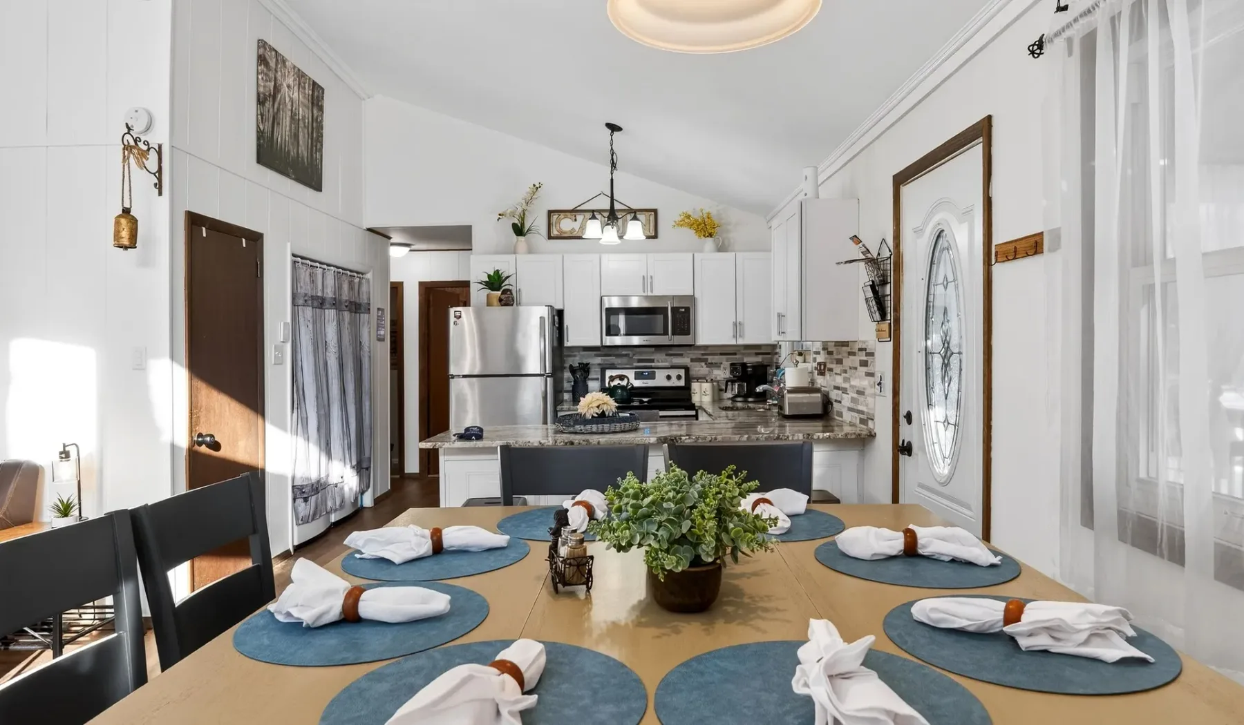 A dining area with a set table and an open kitchen in the background.