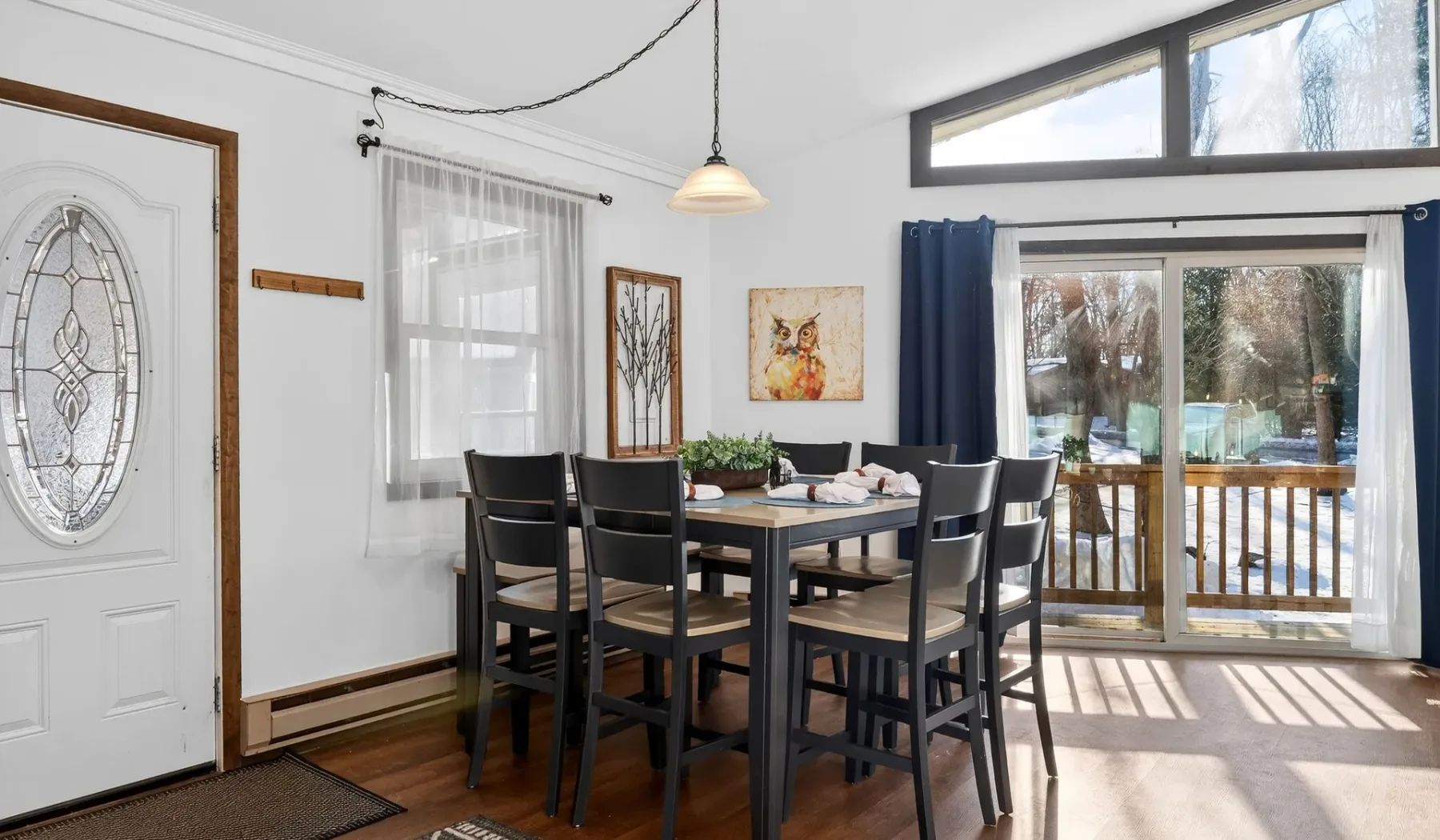 A bright dining area with a table and chairs beside large windows opening onto a deck.