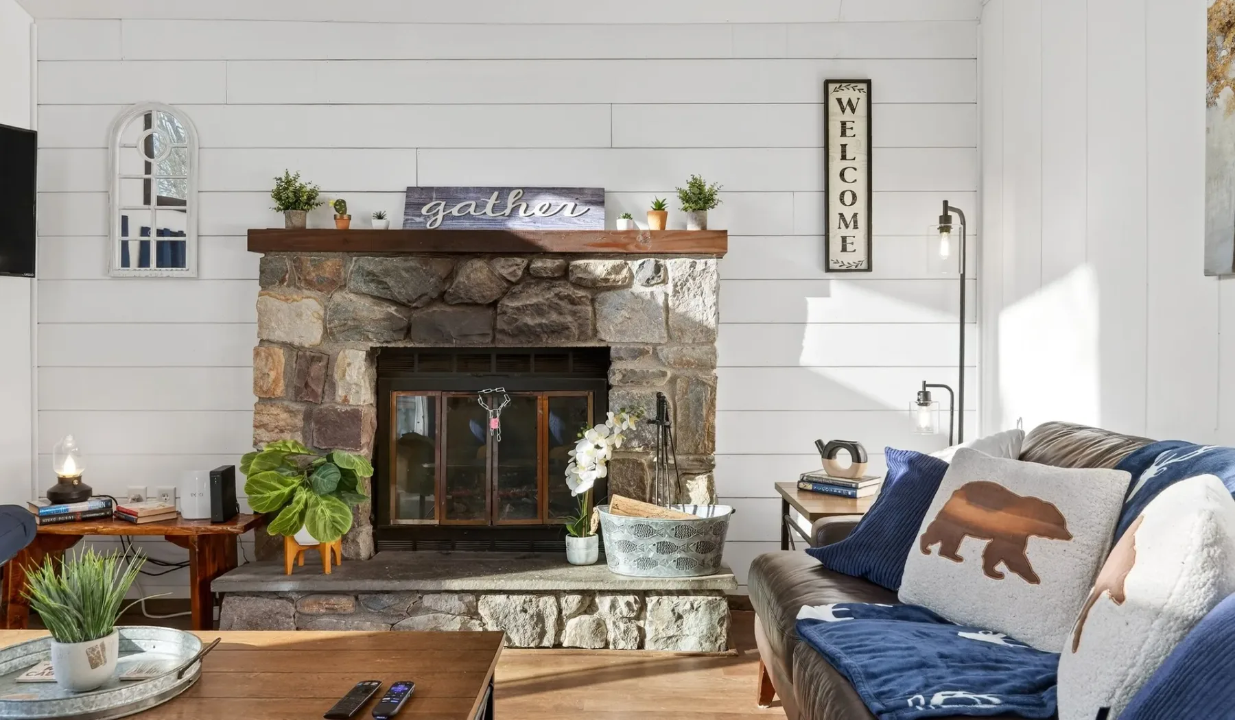 A bright living room with a stone fireplace and blue seating.