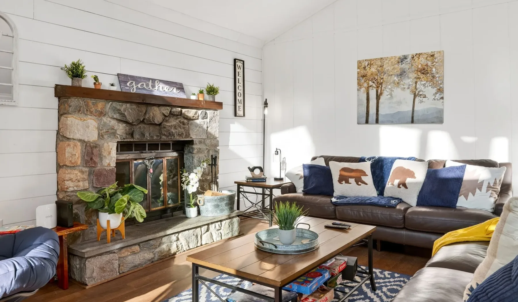 A bright living room with a stone fireplace and seating around a coffee table.