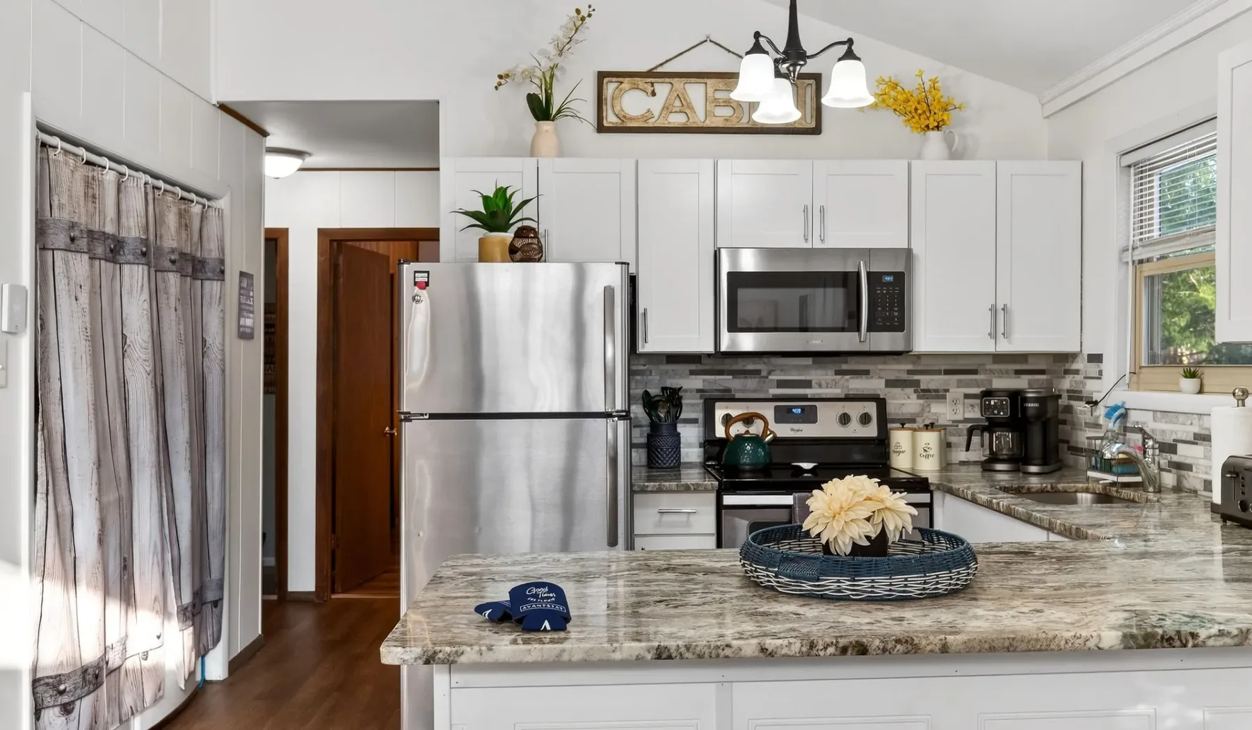 A bright kitchen with white cabinets, stainless steel appliances, and a large island.