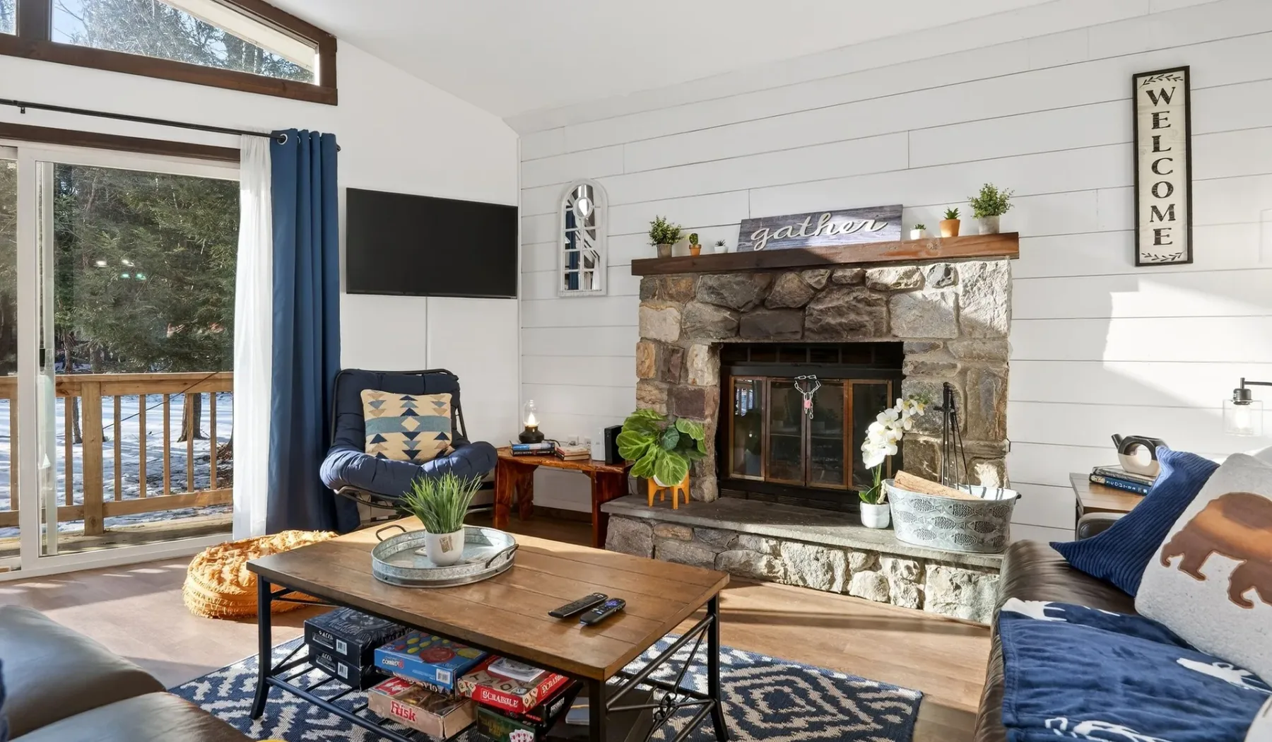 A living room with a stone fireplace, seating, and a wooden coffee table.
