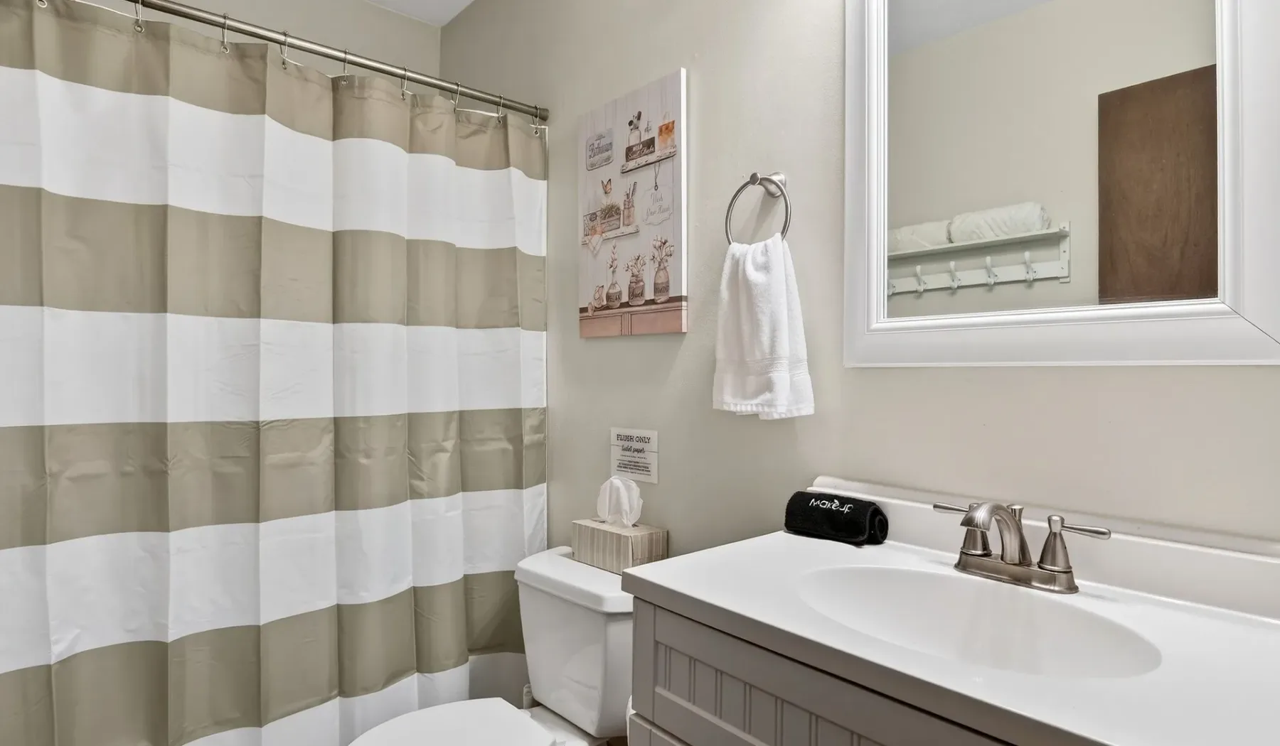 A bathroom with a striped shower curtain, sink, and mirror.