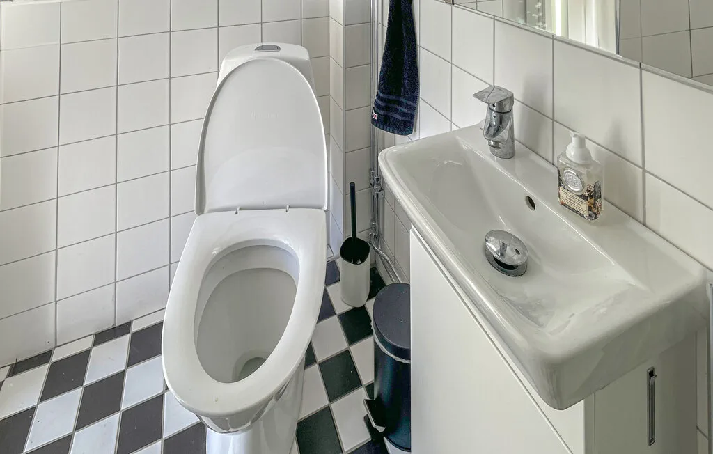 Un baño con azulejos, un inodoro y un lavabo.