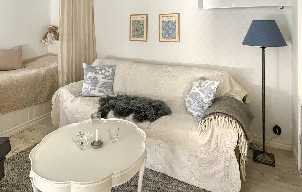 Un salón luminoso con un sofá blanco, cojines estampados y una mesa de centro redonda.