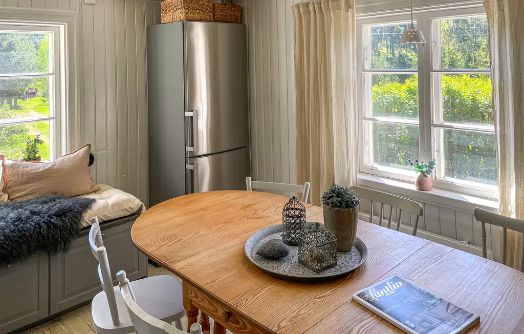 Un comedor luminoso con una mesa de madera junto a grandes ventanas.