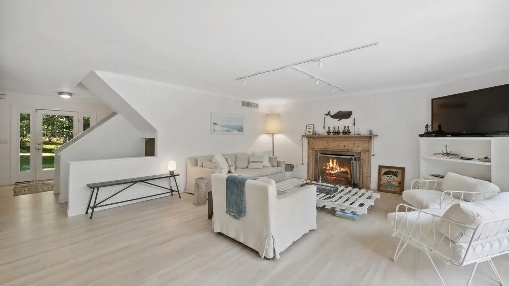Una sala luminosa con asientos dispuestos alrededor de una chimenea y un televisor.