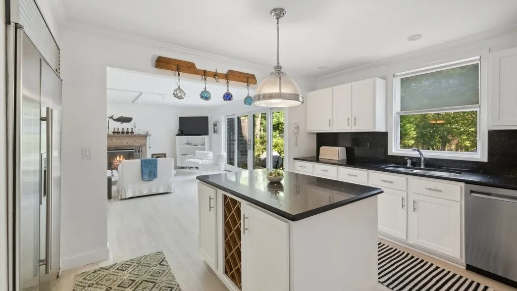 Una cocina luminosa con una isla central se abre a una sala de estar.
