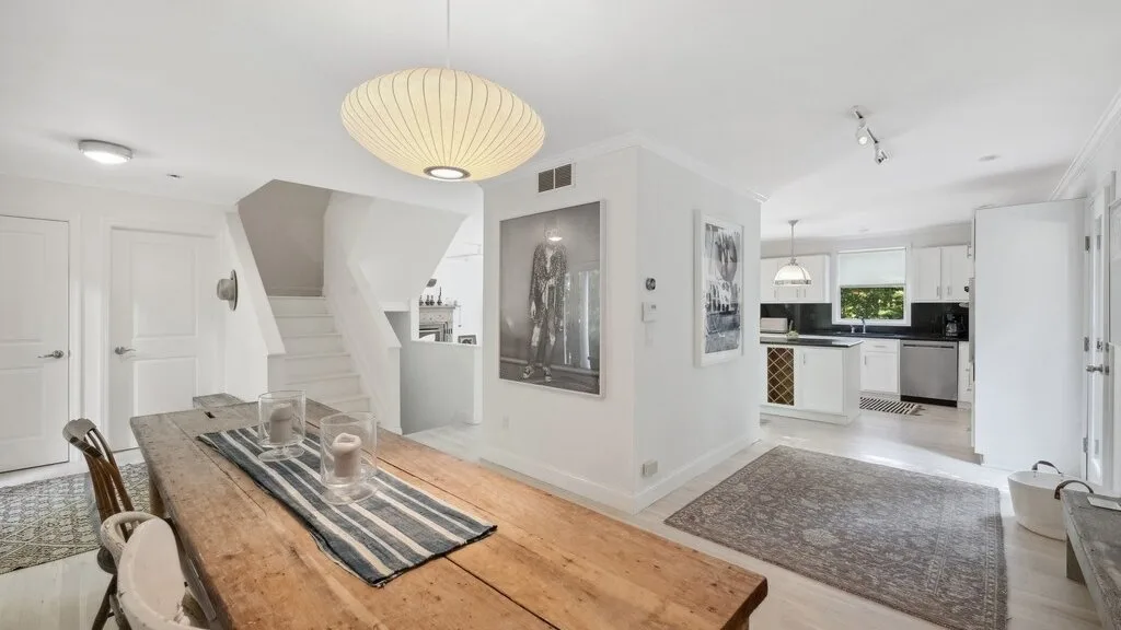 Un comedor y cocina diáfanos y luminosos con una larga mesa de madera.