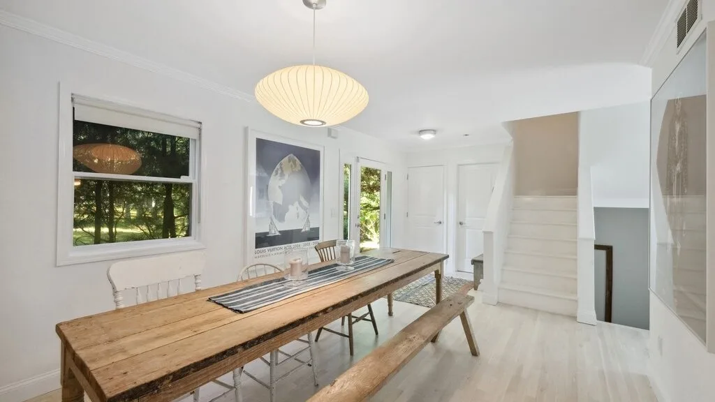 Un comedor luminoso con una larga mesa de madera junto a grandes ventanas.