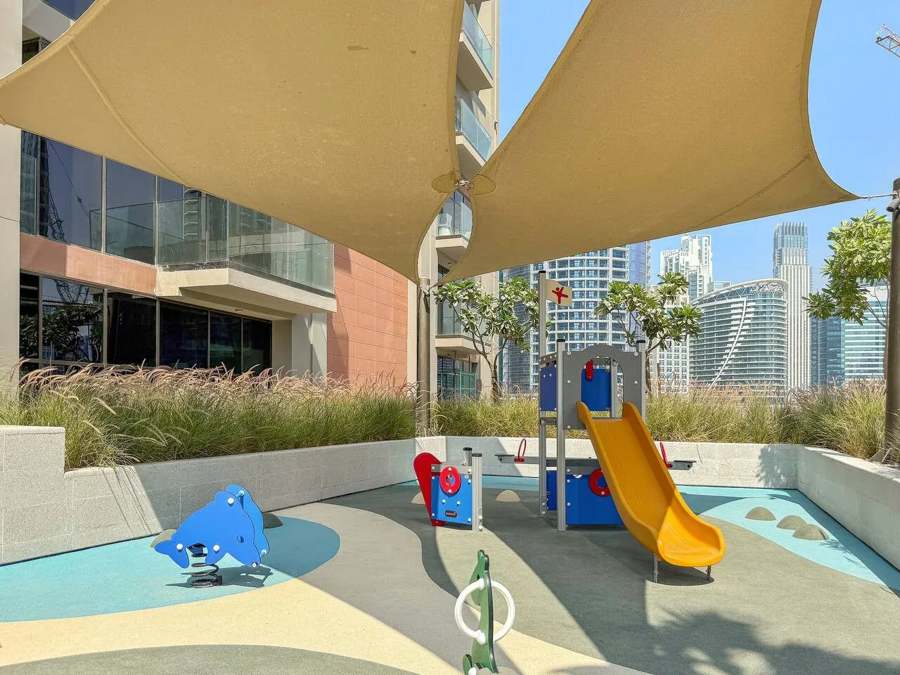 An outdoor playground with a slide and shade sails.