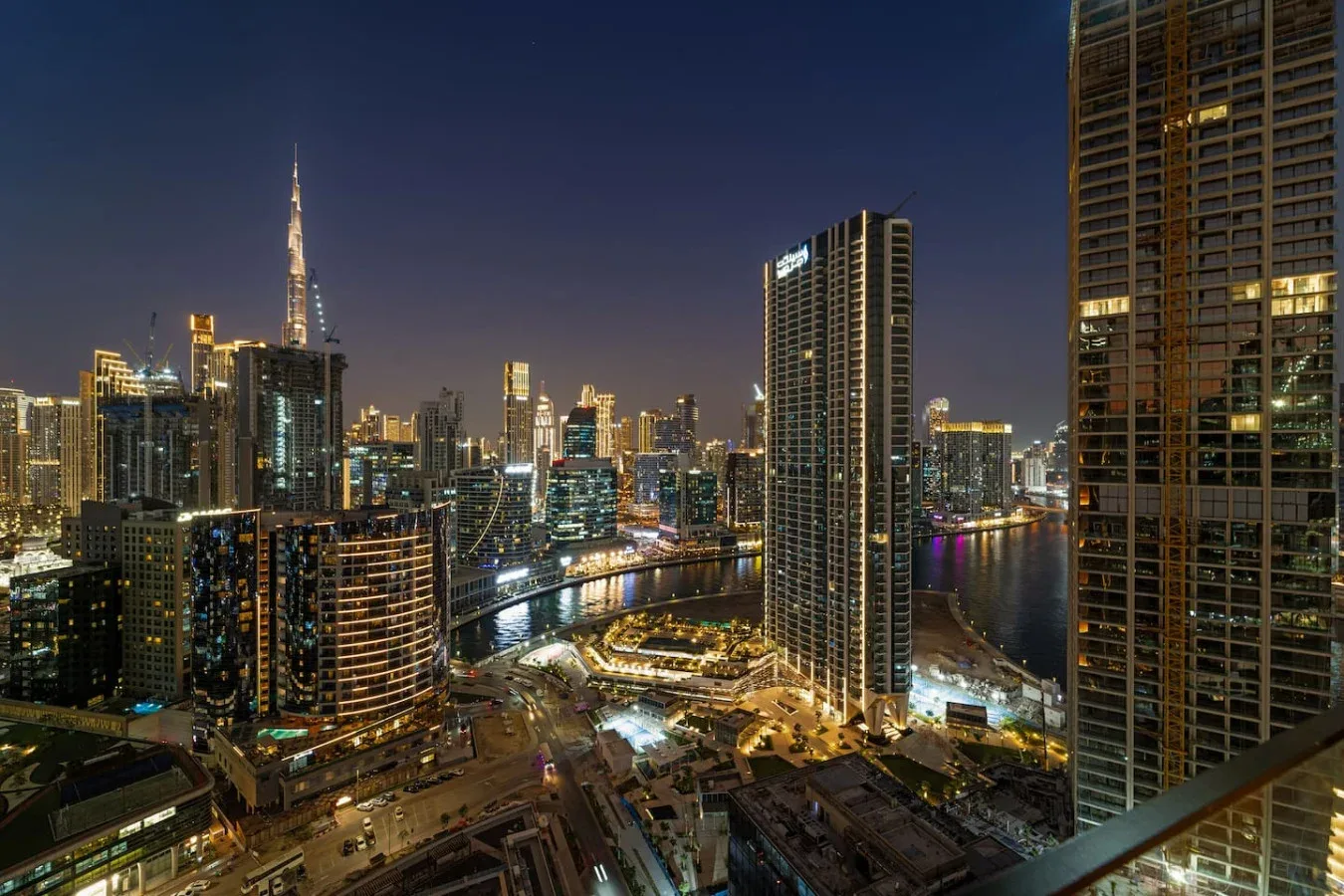 A nighttime city skyline rises above a brightly lit waterfront.