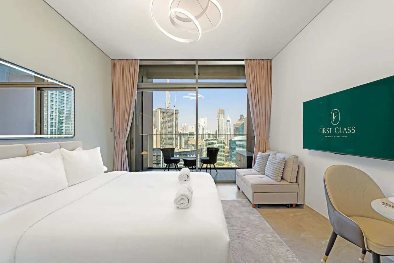 A bright bedroom with a large bed, seating, and windows overlooking city buildings.