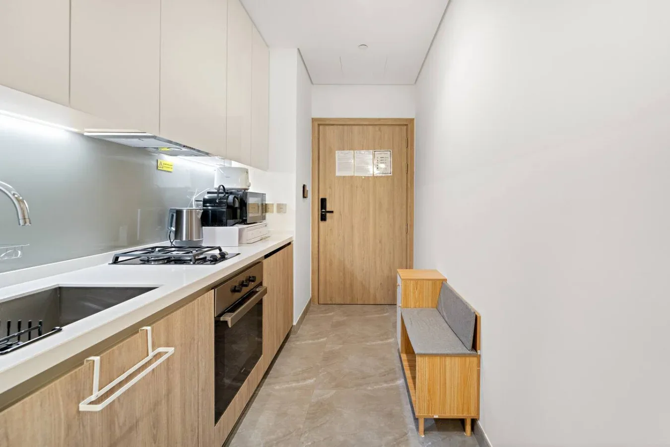 A narrow kitchen with a long counter and a wooden door at the end.