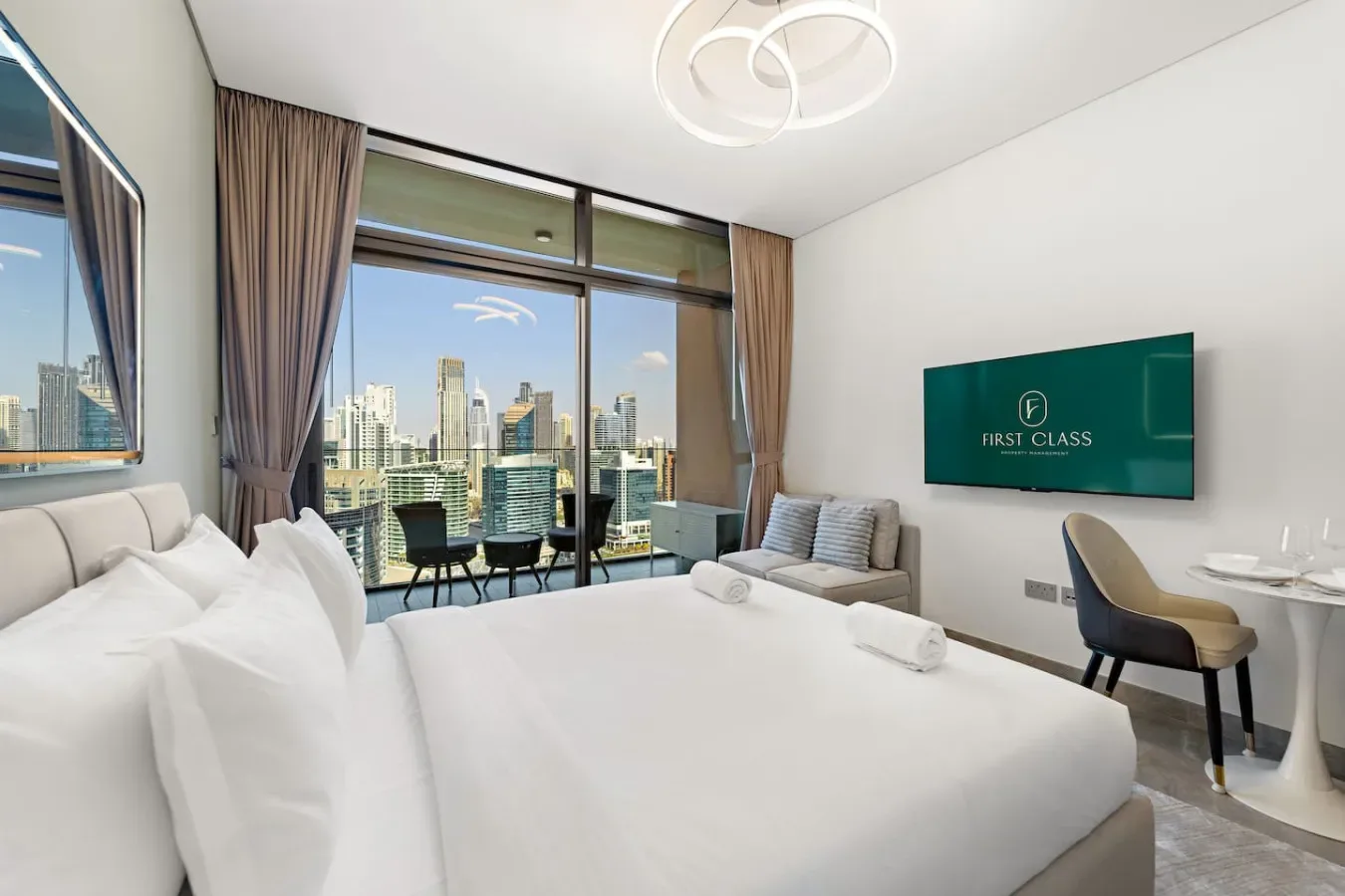 A bright bedroom with a large bed and city views through floor-to-ceiling windows.