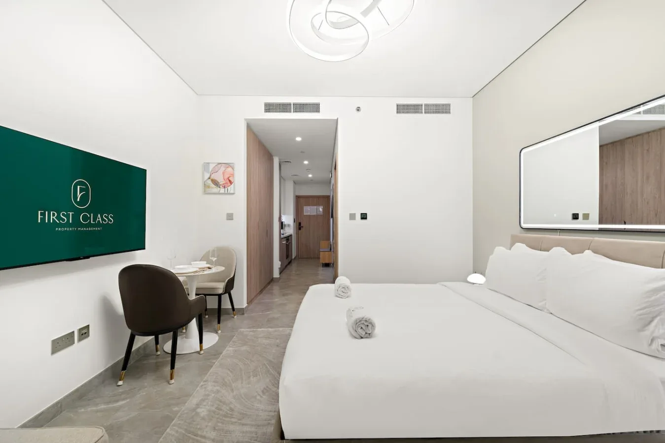A bright bedroom with a large bed and a small desk beside the doorway.