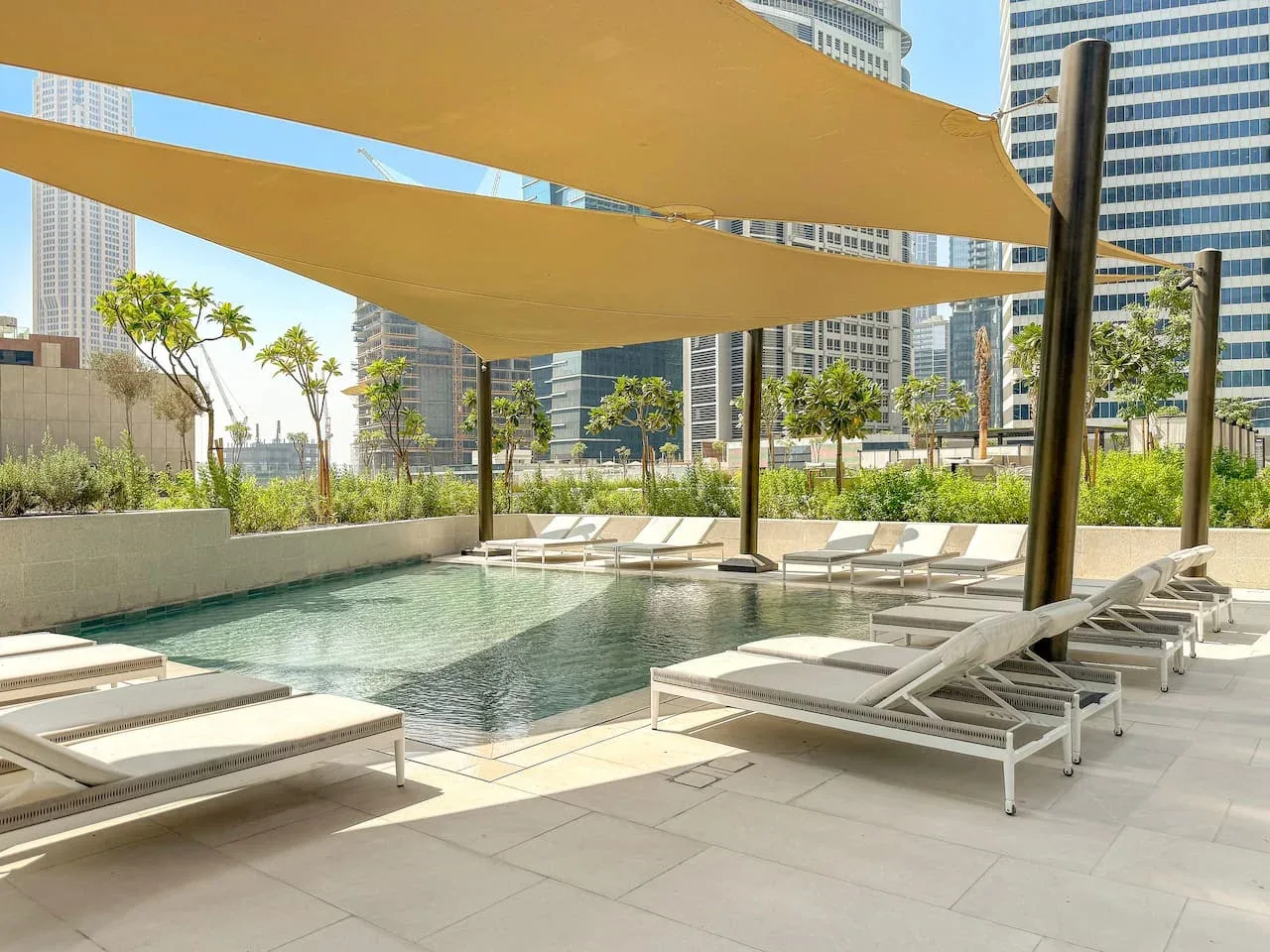 An outdoor pool with lounge seating beneath large shade canopies.