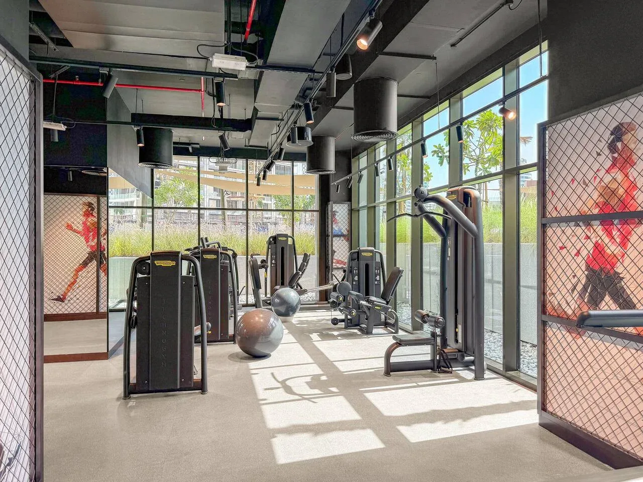 A bright gym with exercise machines and large windows.