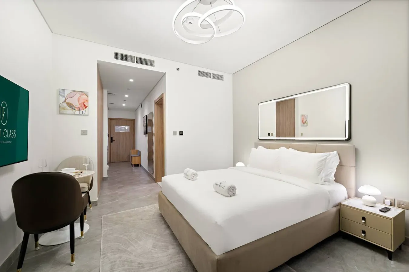 A bright bedroom with a neatly made bed and a hallway beyond.