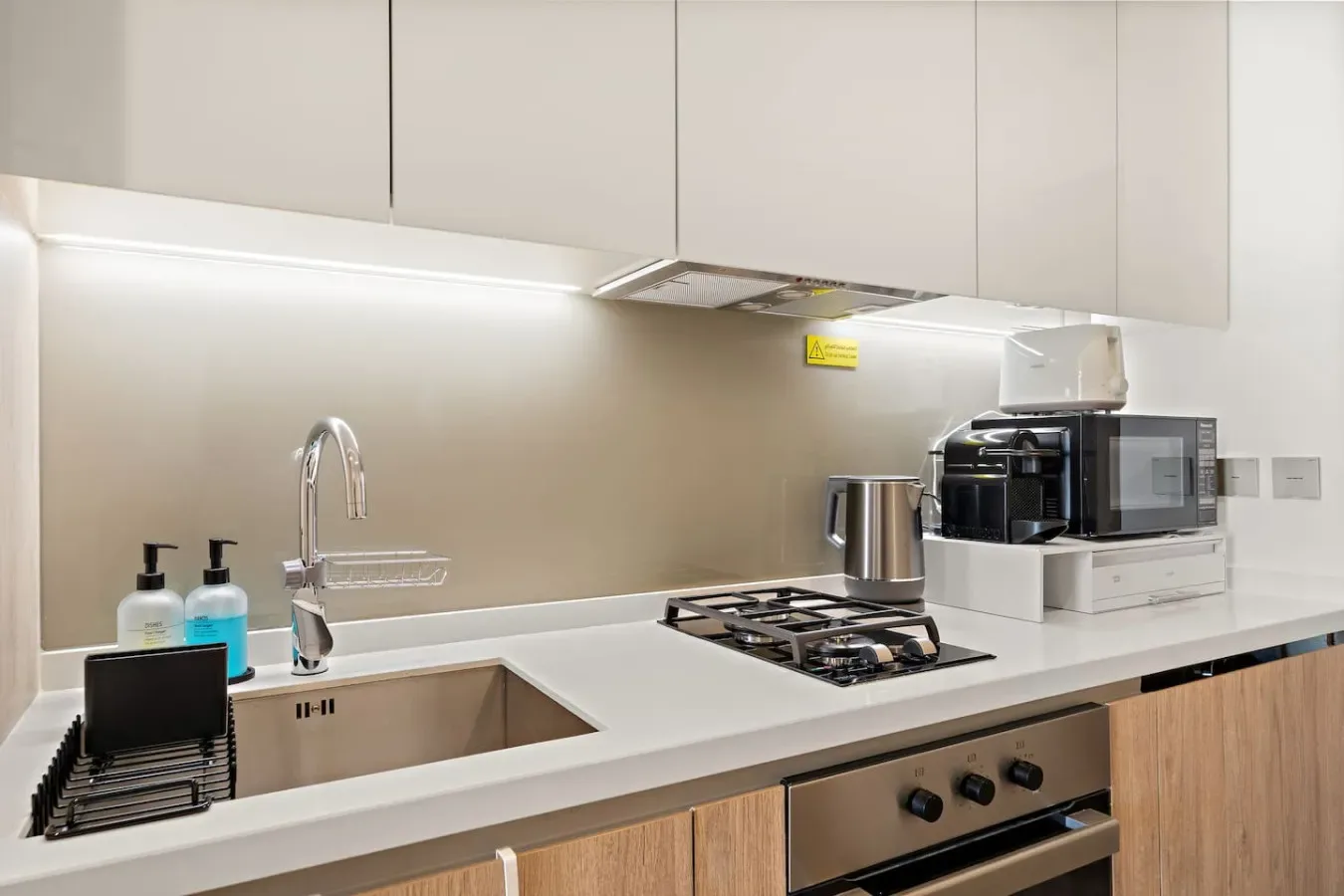 A modern kitchen with a sink, cooktop, and small appliances on the counter.
