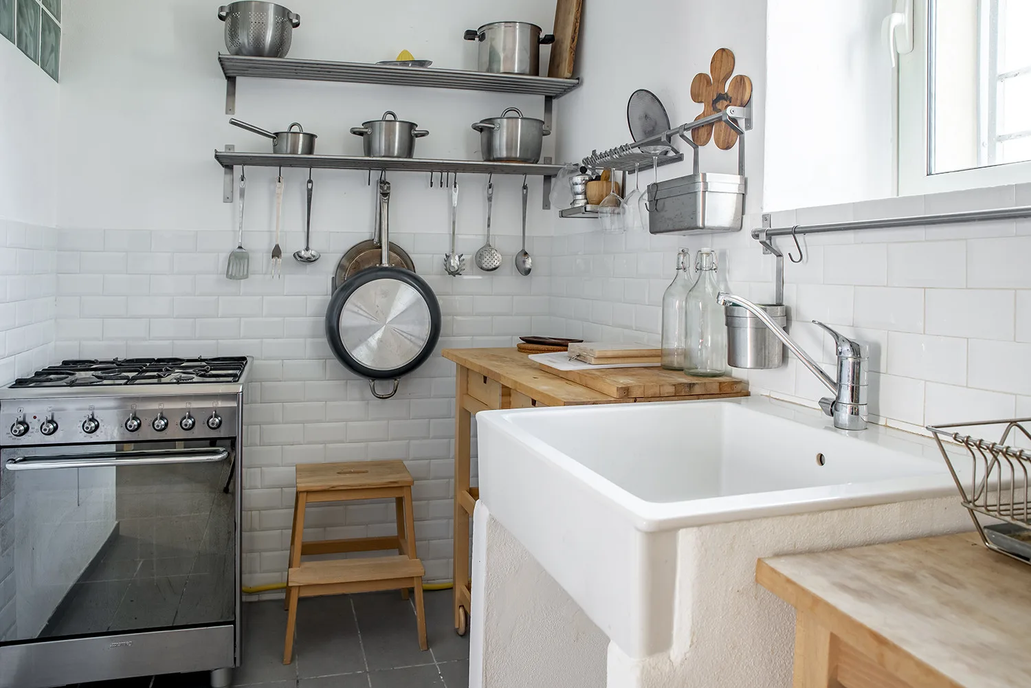 A bright kitchen with a large sink, wooden work surfaces, and hanging cookware.