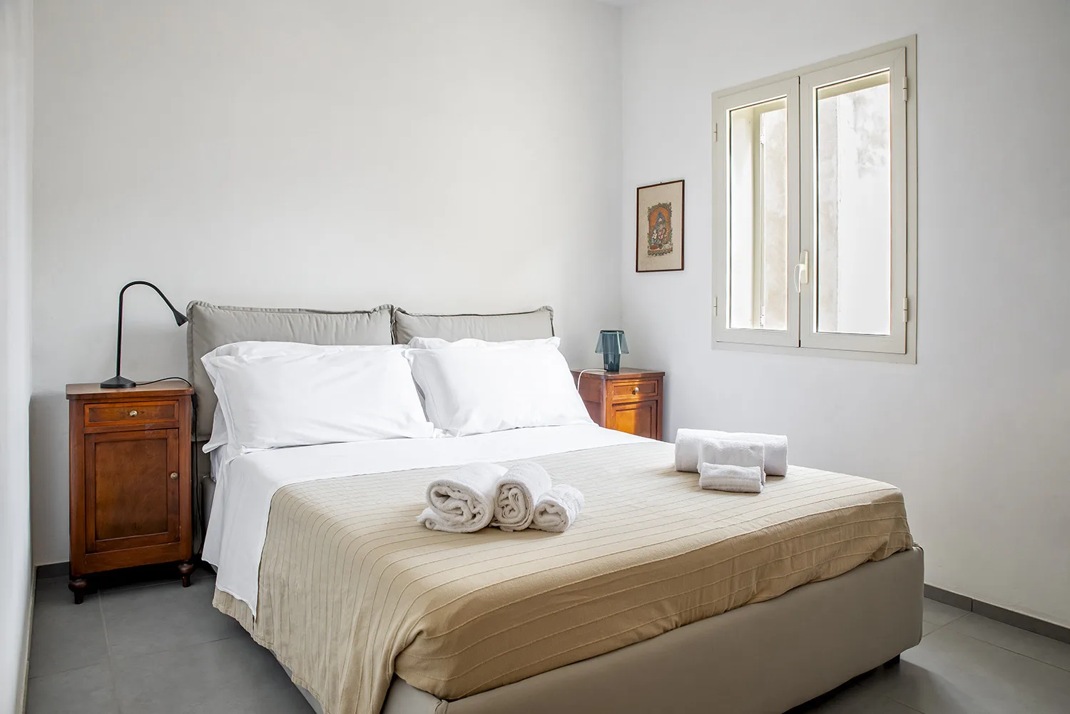 Un dormitorio con una cama bien arreglada y una ventana.