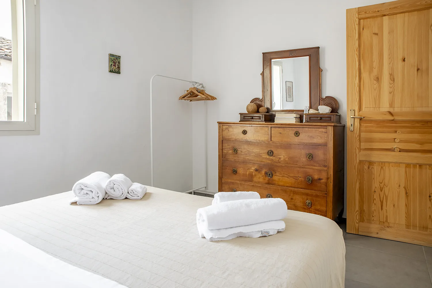 A bedroom with a neatly made bed and wooden dresser.