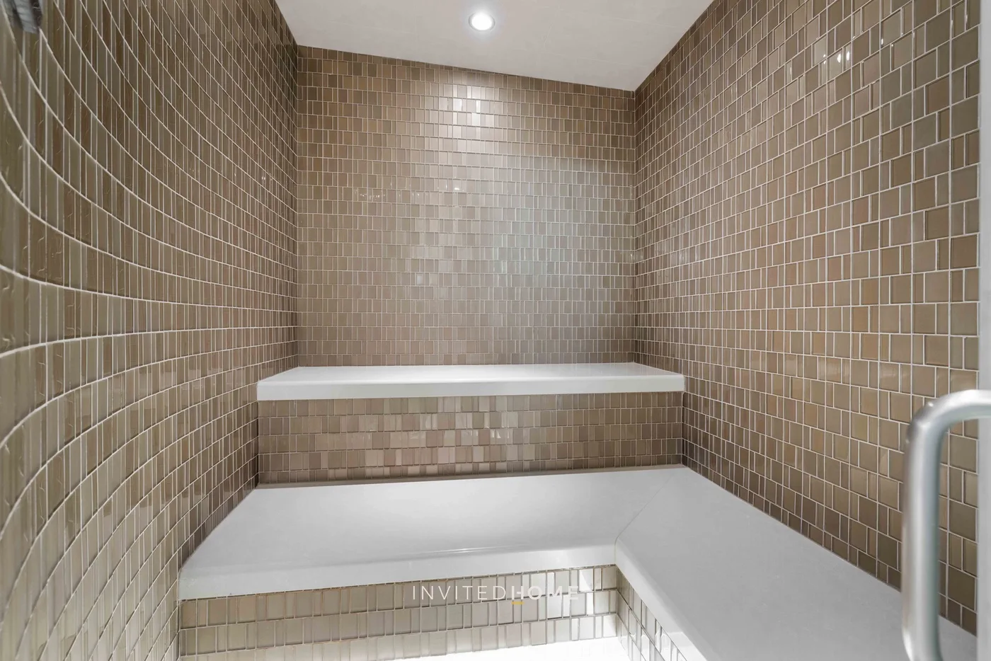 Un baño de vapor alicatado con un banco integrado y una barandilla.