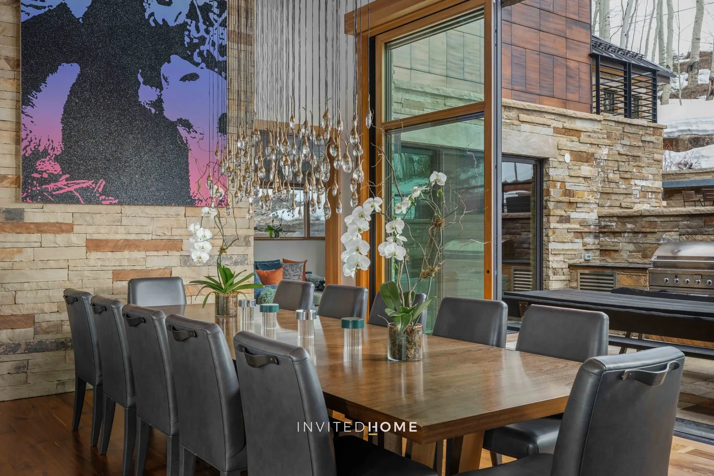 Comedor con una mesa larga de madera y asientos tapizados oscuros.
