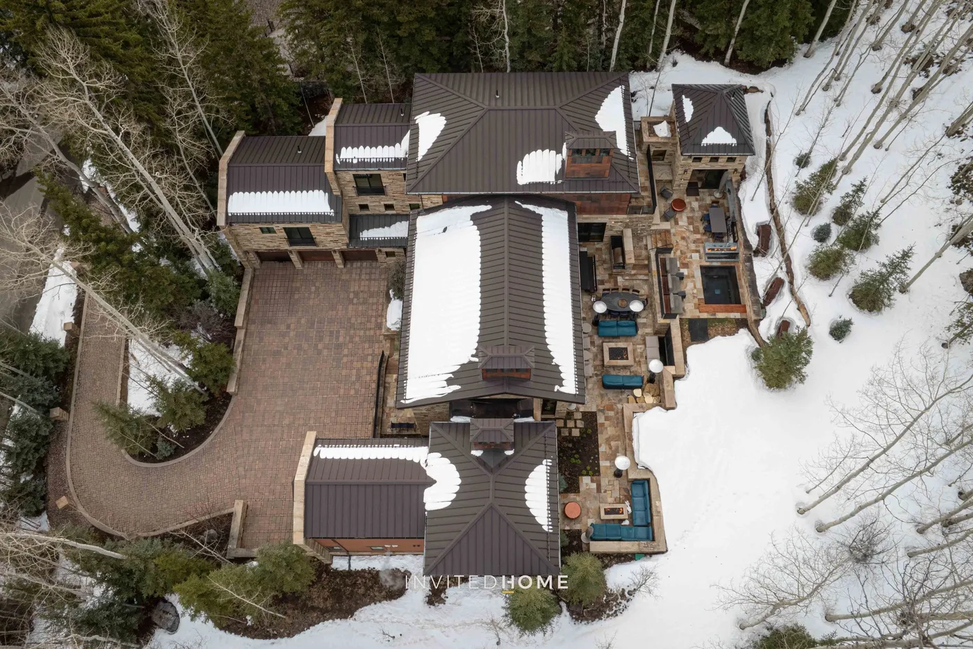 Vista aérea de una casa grande rodeada de árboles cubiertos de nieve.