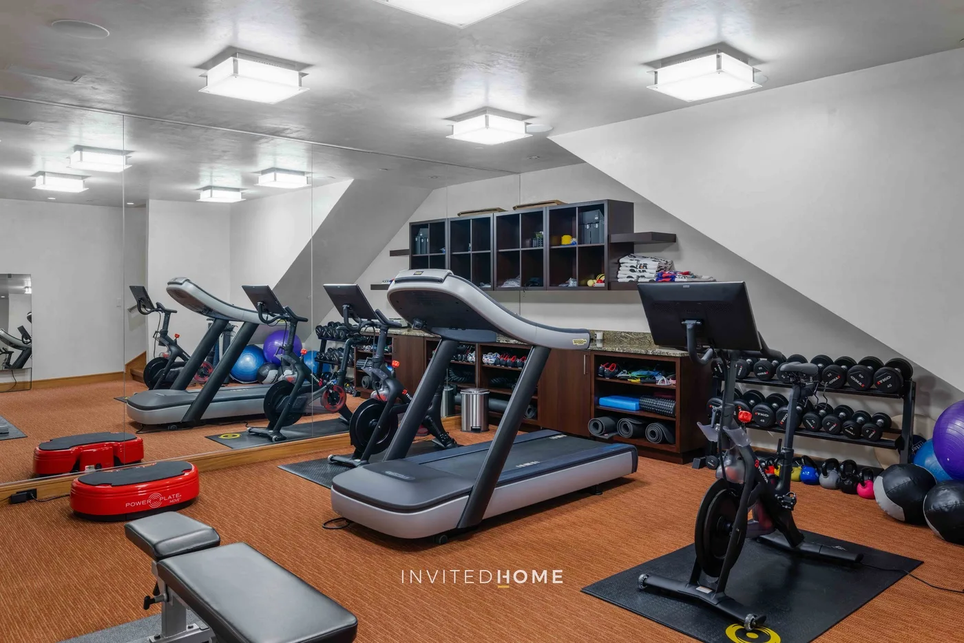 Un gimnasio en casa con cintas de correr, bicicletas estáticas y pesas.