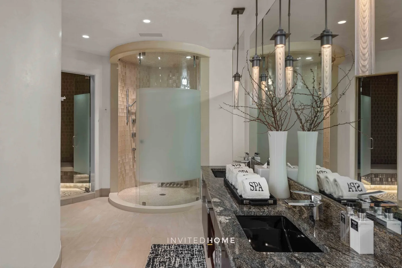 Un tocador de baño con lavabo, espejos altos y una ducha curva de vidrio.