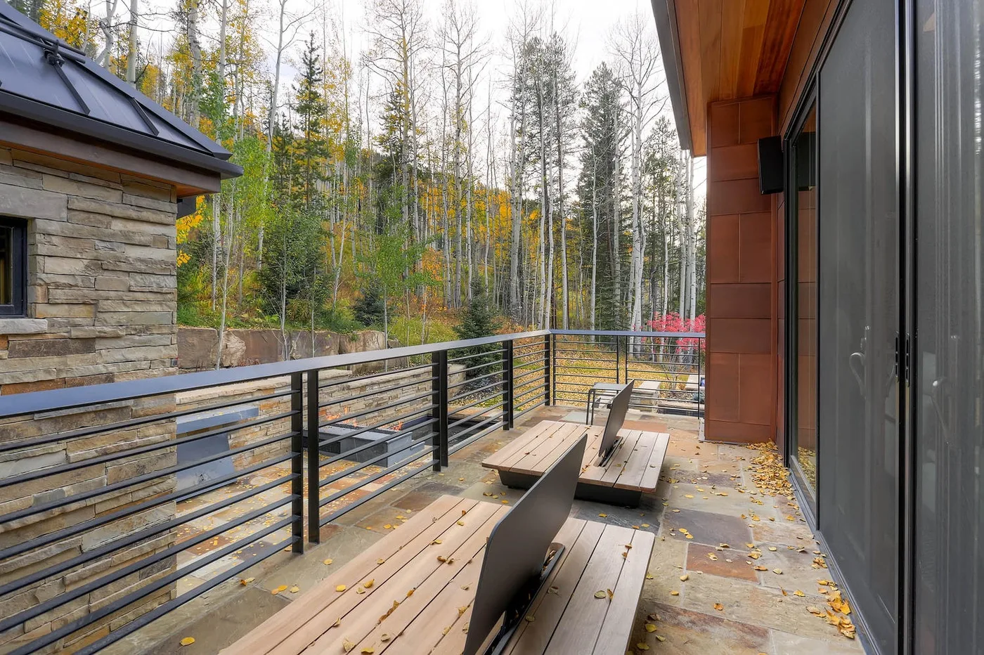 Una terraza exterior con asientos de madera da a un paisaje arbolado.