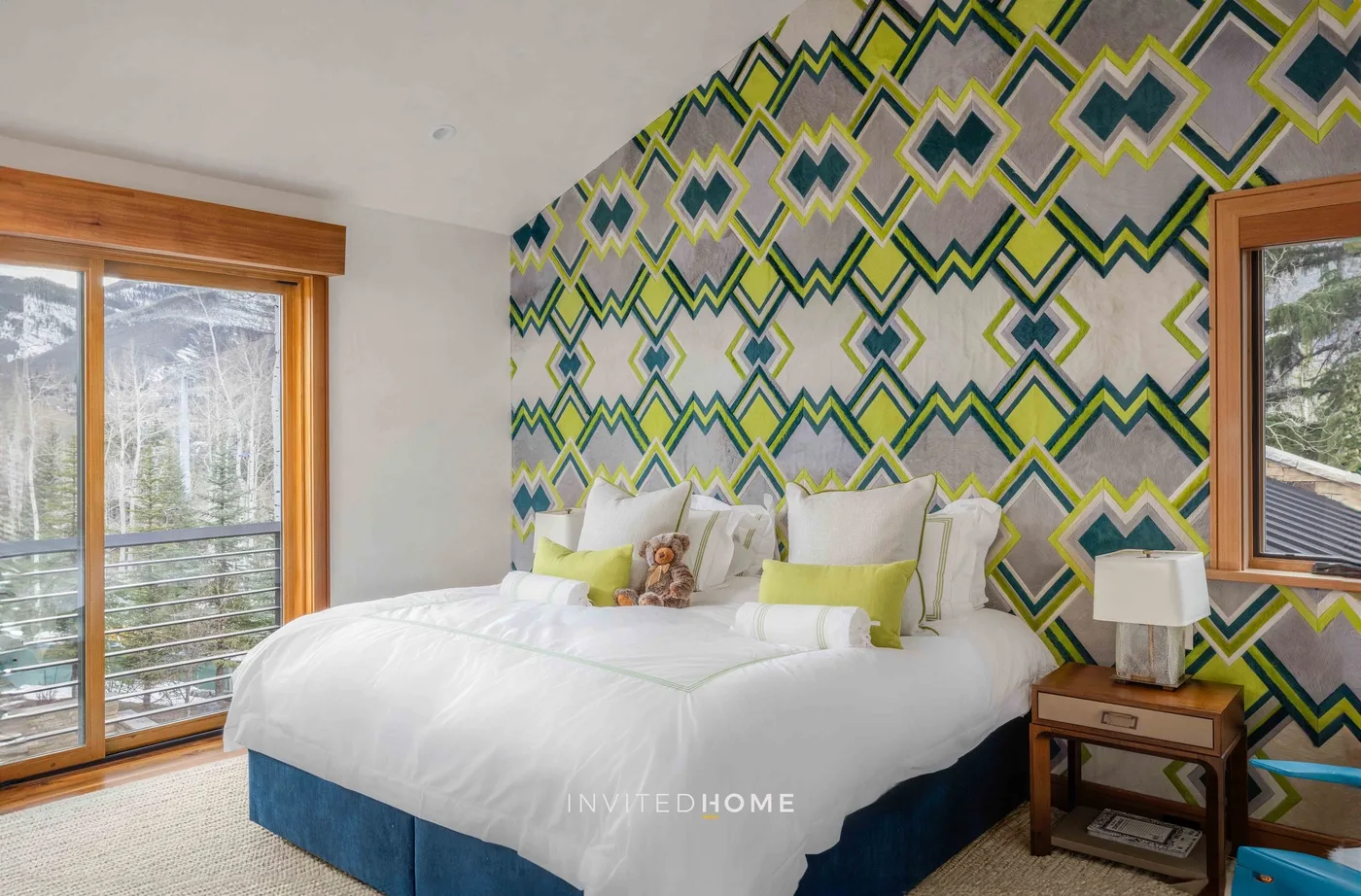 Un dormitorio con una cama frente a una pared de patrones geométricos coloridos.
