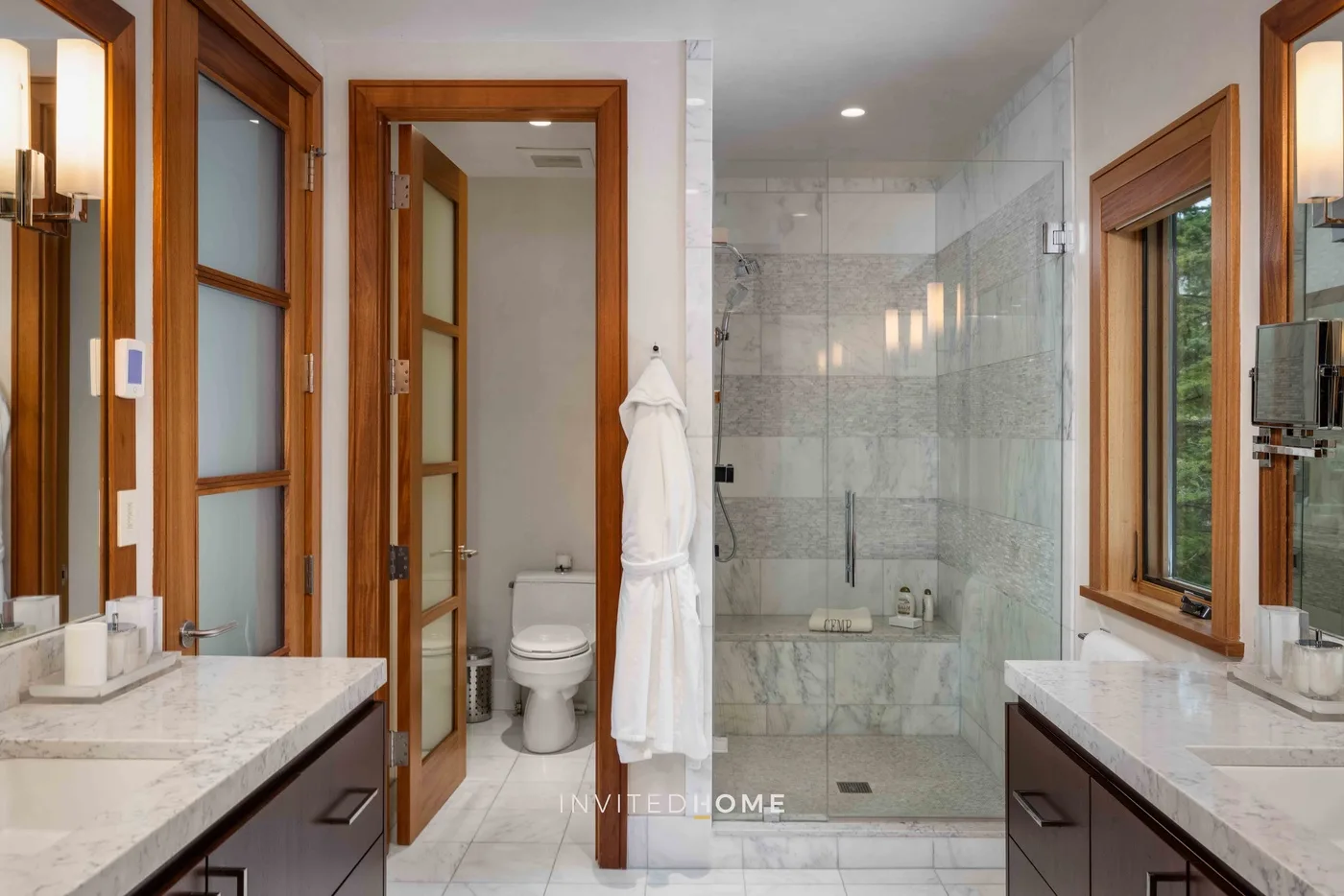 Un baño luminoso con lavabos dobles y una ducha con mampara de vidrio.